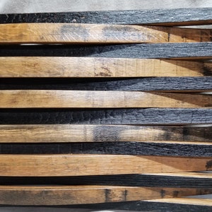 K&ouml;nnte beinhalten: Eine amerikanische Holzflagge aus wiederverwendeten Fassdauben. Die Flagge ist schwarz und braun mit einer Holzmaserung. Die Sterne sind in das Holz gebrannt.