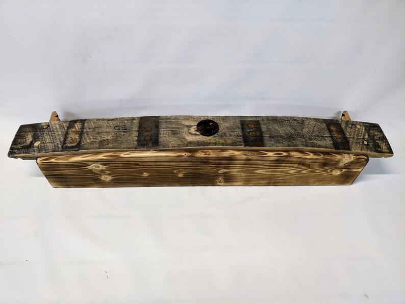 K&ouml;nnte beinhalten: Ein rustikales Holzregal aus recyceltem Holz mit Metallakzenten. Das Regal ist gebogen und hat ein Loch in der Mitte.