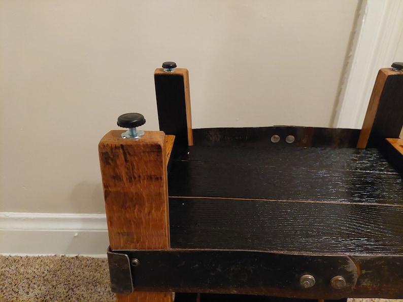 May include: Close-up of a wooden table with a black stained top and black metal accents. The table has four legs with black rubber feet.