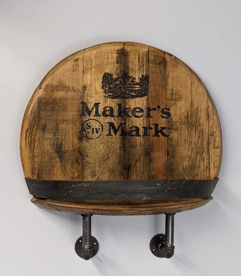 Op de afbeelding: Een houten plank gemaakt van een Maker's Mark whiskeyvat met een zwart metalen plank en twee zwarte metalen pijpbeugels.