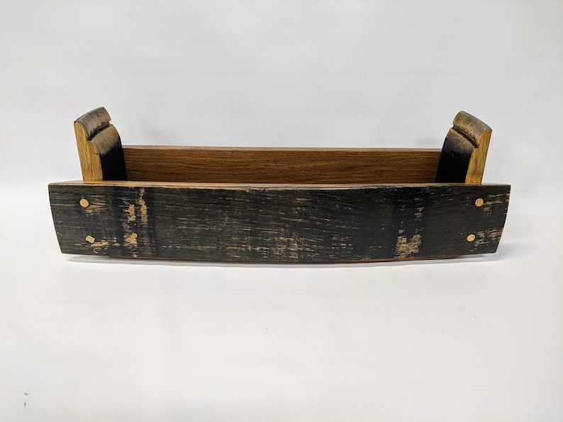 May include: A wooden tray made from a reclaimed whiskey barrel. The tray has a natural wood finish on the inside and a dark stained finish on the outside. The tray has brass accents.