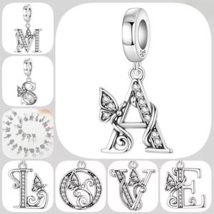 May include: A silver-toned charm featuring the letter A, adorned with clear crystals and a butterfly accent. The charm includes a bail stamped with S925. Additional charms in the collection display various letters and butterfly motifs.
