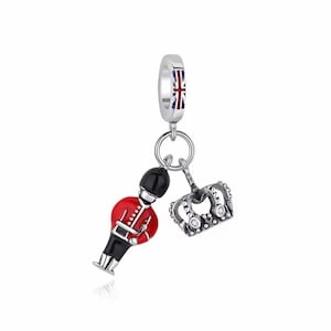 Könnte beinhalten: Ein silberner Charm mit Union Jack-Design, einem Miniatur-Soldaten in Rot und Schwarz und einer silbernen Krone mit klaren Steinen. Der Charm ist für ein Armband oder eine Halskette konzipiert.