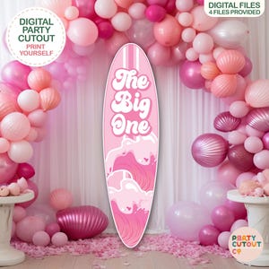 May include: A pink surfboard-shaped party cutout with the text "The Big One" and wave graphics. The background features a pink balloon arch and decorative elements, with text that reads "Digital Party Cutout" and "Print Yourself".