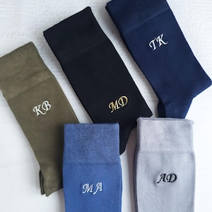 Peut inclure: Cinq paires de chaussettes en tissu de différentes couleurs avec des initiales brodées. Les initiales sont KB, MD, TK, MA et AD.