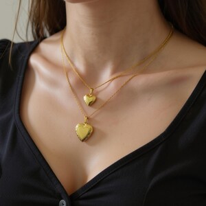 A woman wearing two gold heart-shaped pendants on her neck.