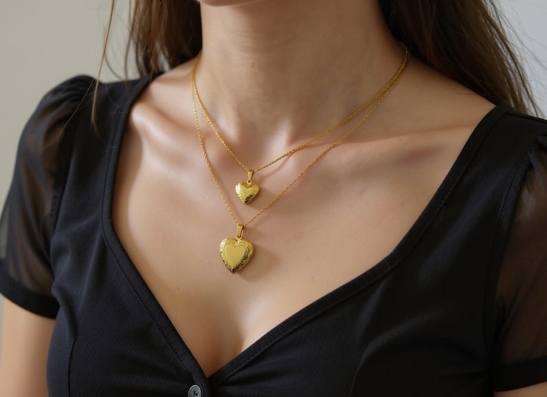 A woman wearing two gold heart-shaped pendants on her neck.