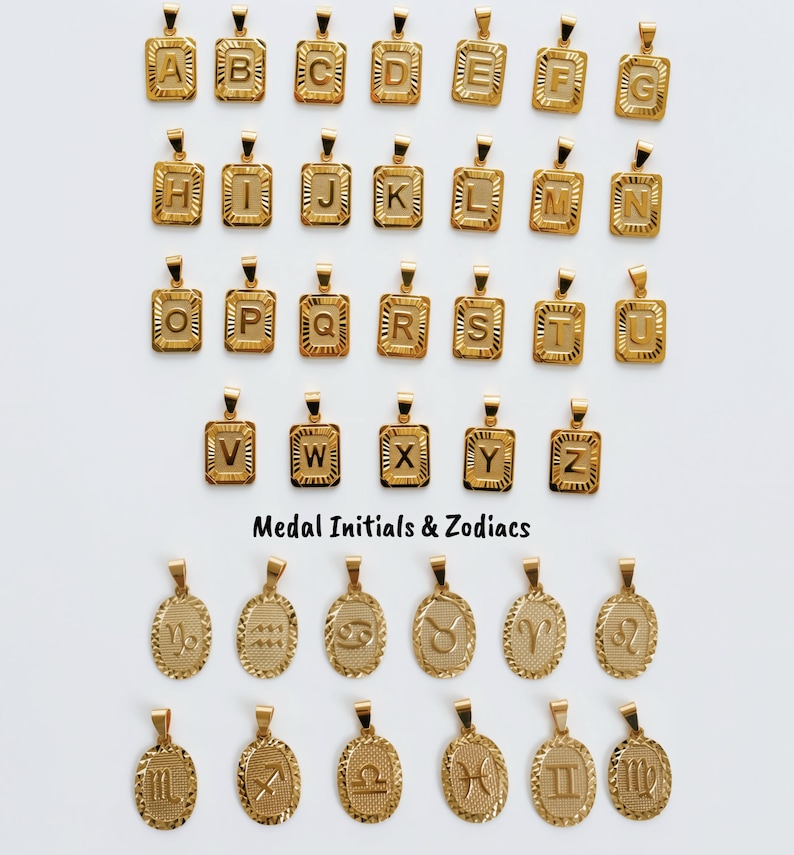 a collection of gold-colored pendants in the shape of letters and zodiac signs, arranged in rows and columns.