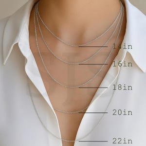 a close-up of a person's neck with multiple silver chain necklaces of varying lengths, ranging from 14 to 22 inches.