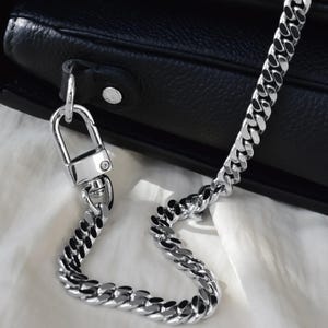 A close-up view of a black leather handbag with a silver metal chain strap.
