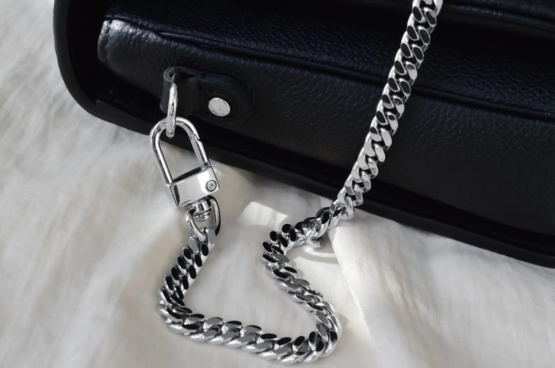 A close-up view of a black leather handbag with a silver metal chain strap.