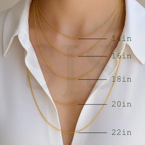 a close-up of a person's neck with multiple gold chain necklaces of varying lengths, ranging from 14in to 22in.