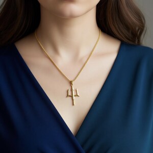 A close-up of a woman wearing a gold necklace with a pendant.
