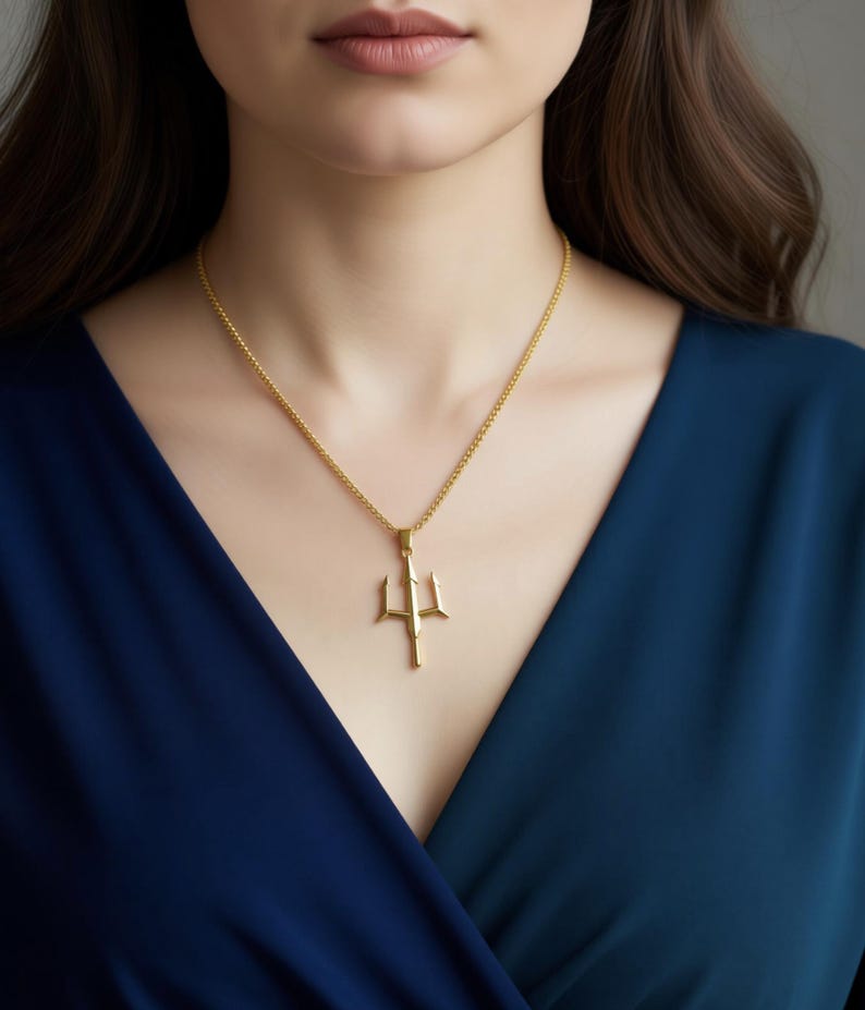 A close-up of a woman wearing a gold necklace with a pendant.