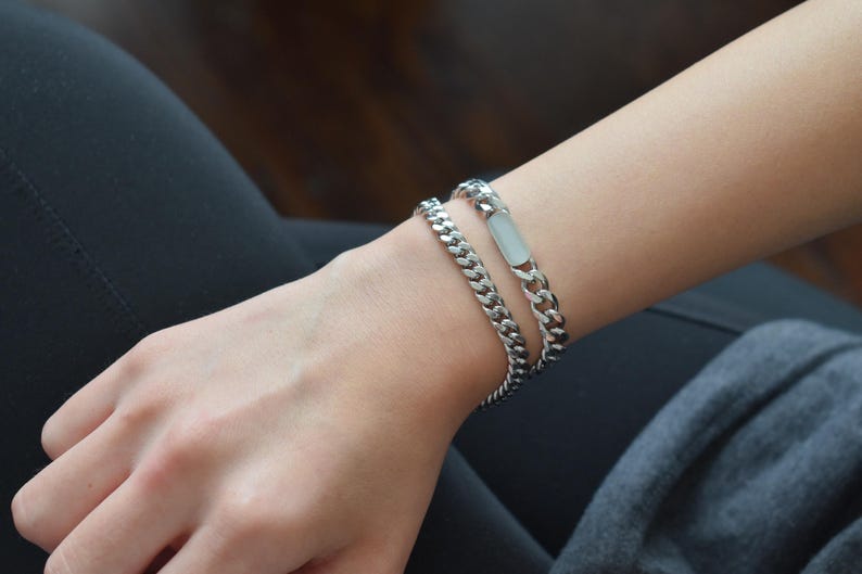 A close-up view of a person's wrist wearing two silver metal bracelets.