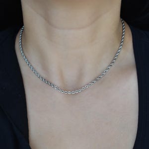 A close-up view of a person wearing a silver chain necklace.