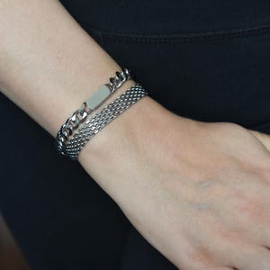 A close-up view of a person's wrist wearing two silver bracelets.