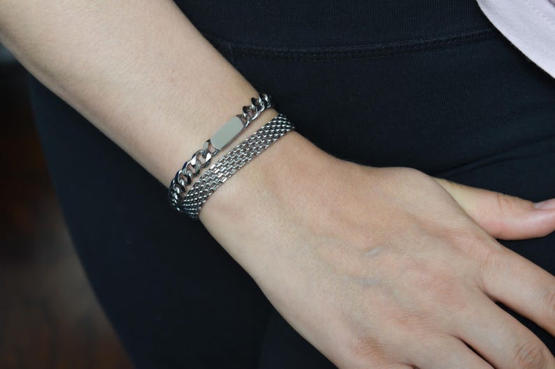 A close-up view of a person's wrist wearing two silver bracelets.