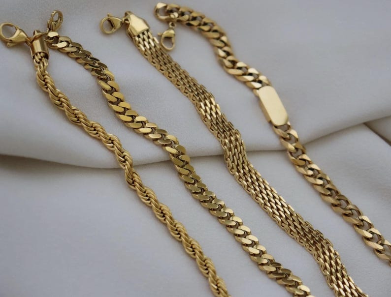 a collection of gold necklaces with various designs and lengths, arranged on a white background.