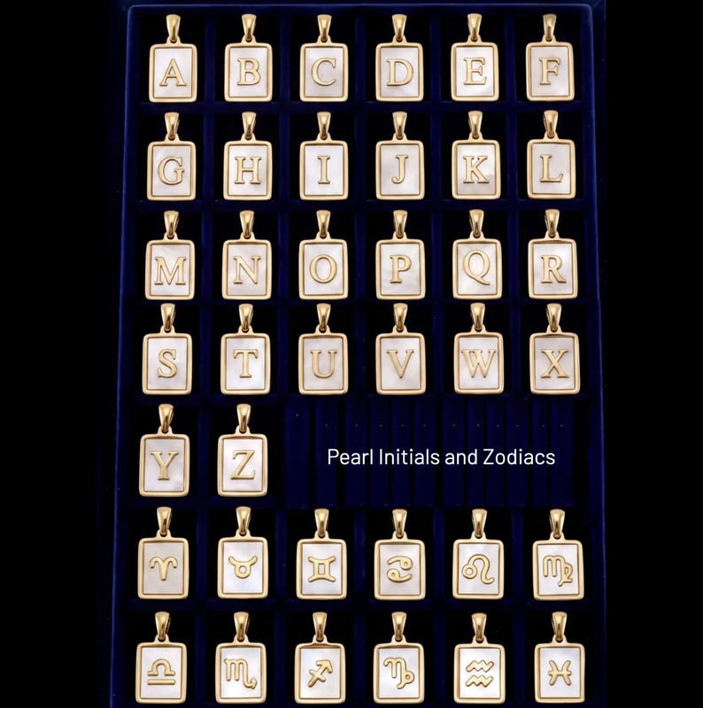 a collection of gold-colored pendants in the shape of letters of the alphabet, arranged in a grid-like pattern on a dark background.