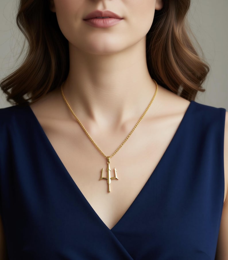 A woman wearing a gold necklace with a pendant is shown in the image.