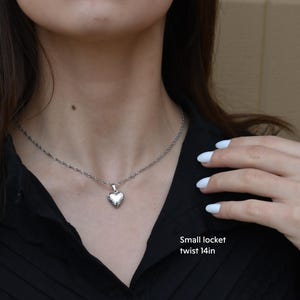 a woman wearing a necklace with a heart on it