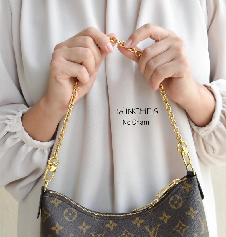 A person is holding a brown and gold Louis Vuitton handbag with a gold chain strap.