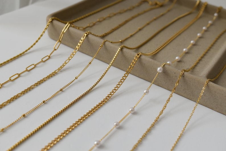 A collection of various gold necklaces and chains arranged on a tray or display.