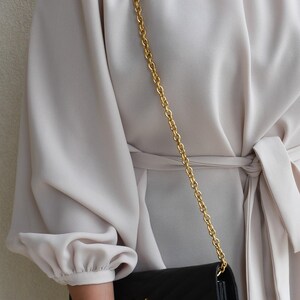 a woman in a white dress holding a black purse