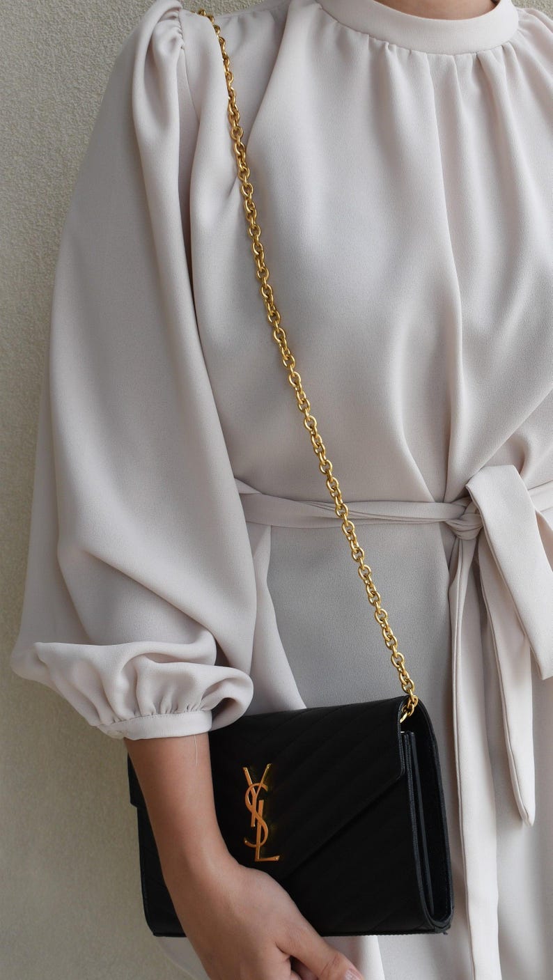 a woman in a white dress holding a black purse