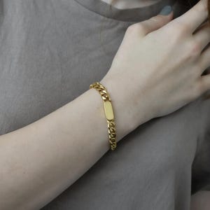 A close-up view of a person's wrist wearing a gold-colored bracelet.