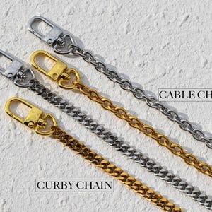 May include: Close-up of four metal chain straps with lobster clasps. Two are silver, and two are gold. One silver chain is labeled "CABLE CHAIN", and one gold chain is labeled "CURBY CHAIN". The chains are on a textured white surface.