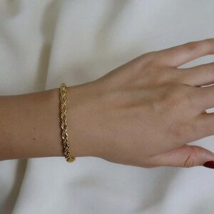 A gold bracelet is worn on a person's wrist.