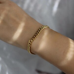 A gold bracelet is worn on a person's wrist.