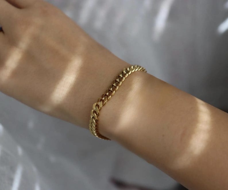 A gold bracelet is worn on a person's wrist.