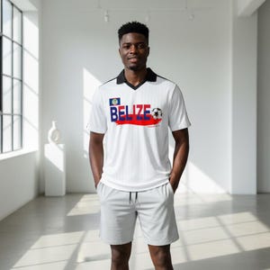 May include: White soccer jersey and gray shorts. The jersey has a black collar and the word "BELIZE" in blue and red with a soccer ball graphic. The shorts have a drawstring.