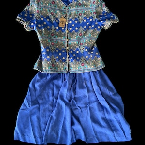 May include: A blue and gold patterned blouse with short sleeves and a matching blue skirt. The blouse has a button-up front and a small tag that says "Country Road".