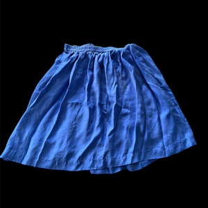 May include: A blue skirt with a gathered waistband. The skirt is made of a soft, lightweight fabric.