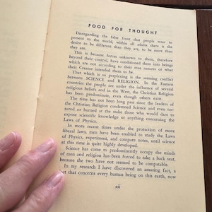 May include: Open book page with the title "FOOD FOR THOUGHT" and text discussing the conflict between science and religion. The page is yellowed with age, and the text is in black. A hand is visible.