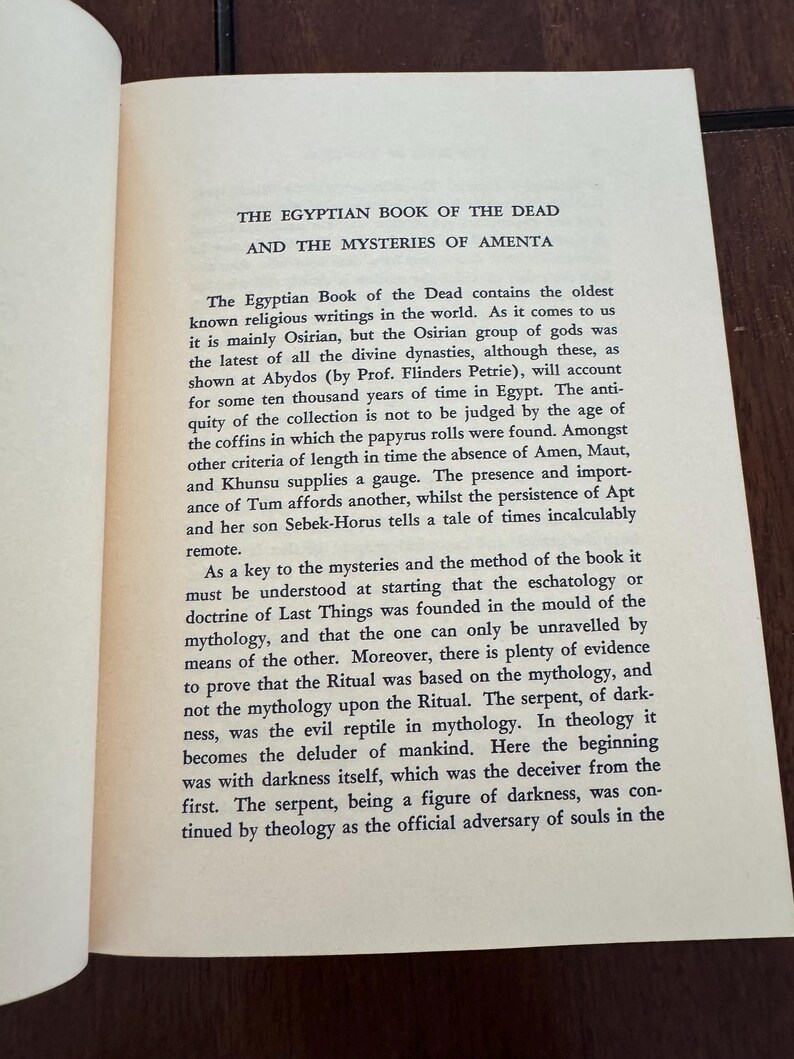 May include: Open book with text titled "THE EGYPTIAN BOOK OF THE DEAD AND THE MYSTERIES OF AMENTA." The text describes the ancient Egyptian religious writings, discussing Osirian gods, mythology, and rituals.