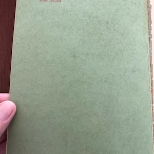 May include: Open book with a light green cover. The text "TAFT BOOK EXCHANGE" is printed in red at the top, along with the address and phone number. The book's pages are visible on the right side.