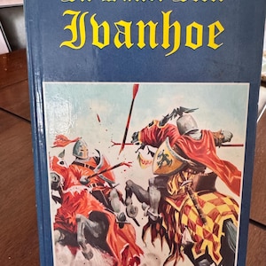 May include: A hardcover book titled "Ivanhoe" by Sir Walter Scott. The cover is blue with yellow lettering. The illustration depicts two knights on horseback in battle, with red and yellow accents.