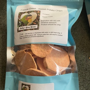 May include: A blue resealable bag with a white label that reads "Freeze Dried - Sweet Potato Chips" and "Holly's Yum Yums". The bag contains a variety of sweet potato chips. The label also includes the text "Contains: Sweet Potato", "Expiration will vary with moisture exposure. Product should be crisp." and "Best Used by: 10/2024".