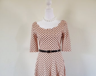 Vintage-inspired peach pull-on dress with black polka dots. Scalloped neckline and 3/4 sleeves