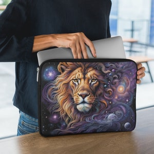 May include: A black laptop sleeve with a colorful design featuring a lion's head with a galaxy background. The lion's mane is flowing and has a purple, blue, and orange color scheme. The galaxy background has stars and planets.