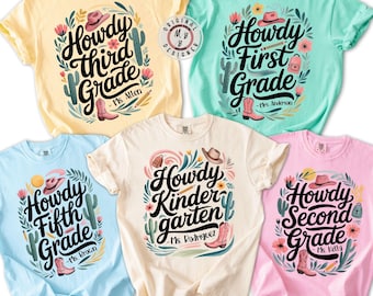May include: Five colorful t-shirts with the words "Howdy" and grade levels, including "Third Grade," "First Grade," "Fifth Grade," "Kindergarten," and "Second Grade." Each shirt features a cowboy hat, boots, and floral designs. The shirts are in various colors.