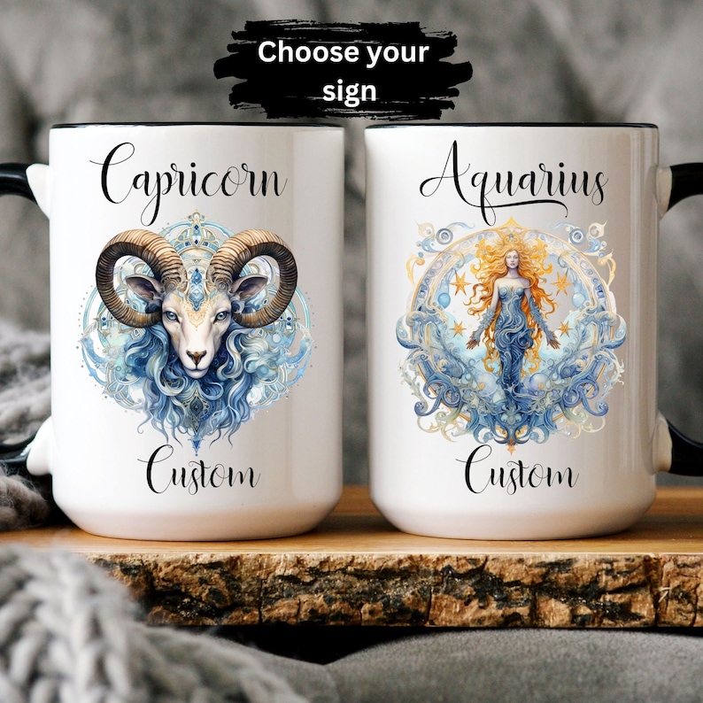 May include: Two white ceramic mugs with black rims. The mug on the left features a blue and white illustration of a Capricorn zodiac sign with the text "Capricorn Custom". The mug on the right features a blue and white illustration of an Aquarius zodiac sign with the text "Aquarius Custom".