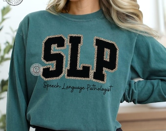 May include: Teal-colored sweatshirt with the letters "SLP" in black with a leopard print outline. The text "Speech Language Pathologist" is below the letters. The sweatshirt has a round neckline and long sleeves.