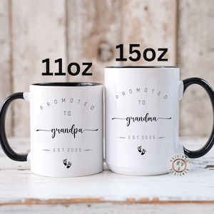 May include: Two white ceramic mugs with black handles and black rims. The 11oz mug says "Promoted to Grandpa Est. 2025" with a footprint symbol. The 15oz mug says "Promoted to Grandma Est. 2025" with a footprint symbol.