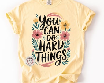 May include: A yellow t-shirt with a floral design and the text "You can do hard things".